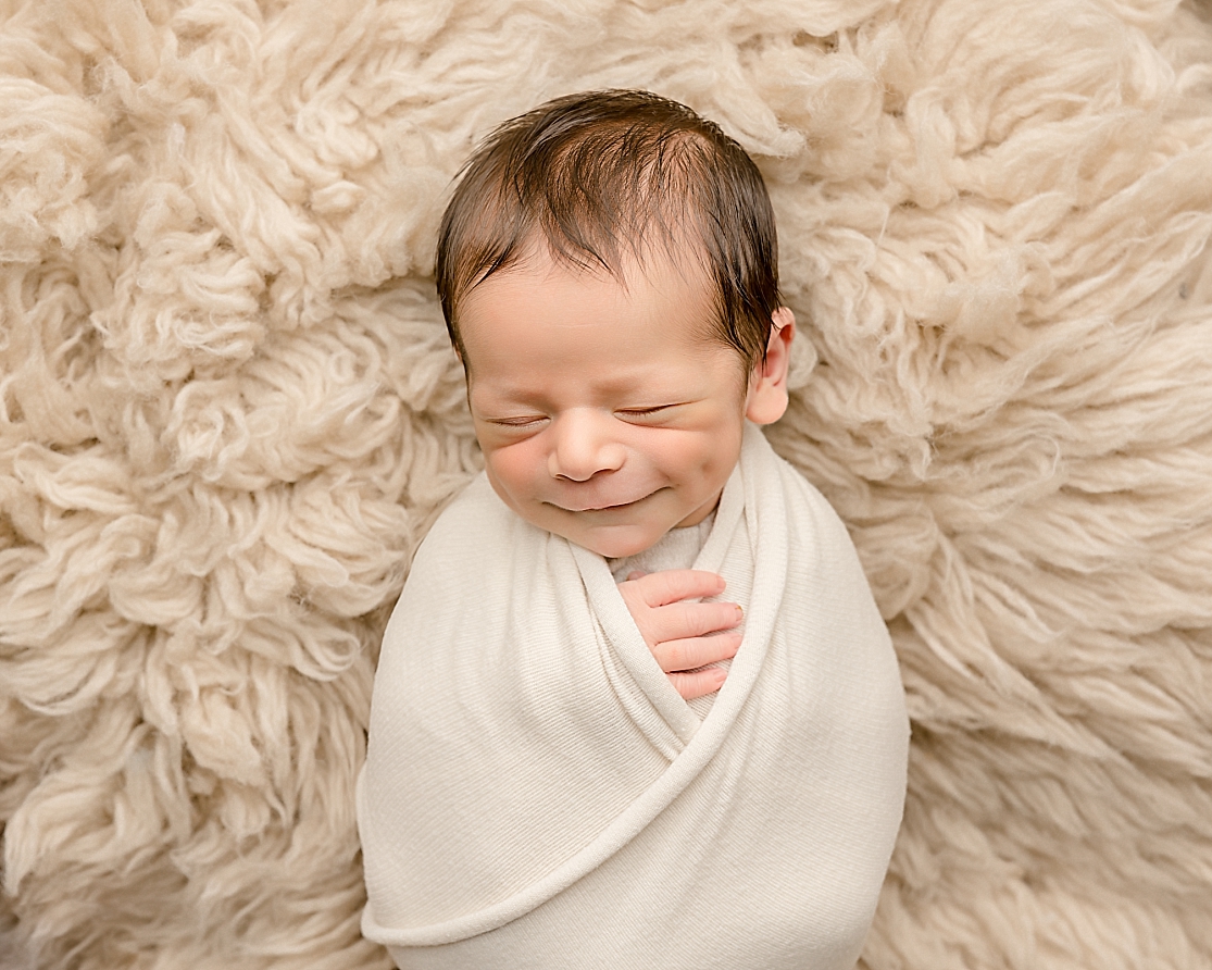baby wrapped in white cloth smiling Le D Bug Boutique