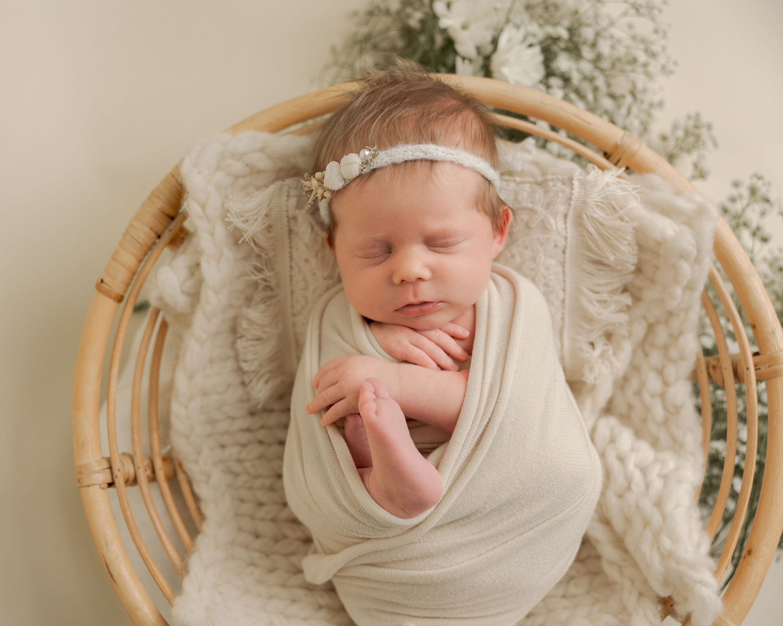wrapped newborn with a headband in a basket baby wit boutique