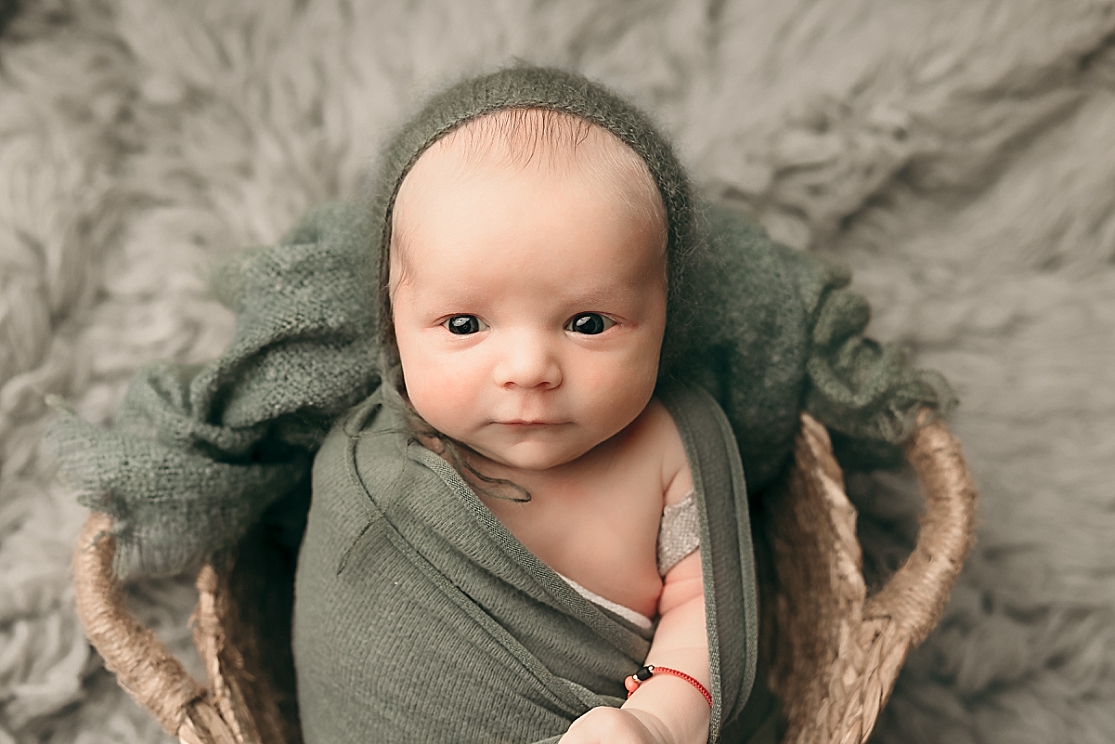 newborn baby wrapped in green sitting in a basket Eco Baby Gear