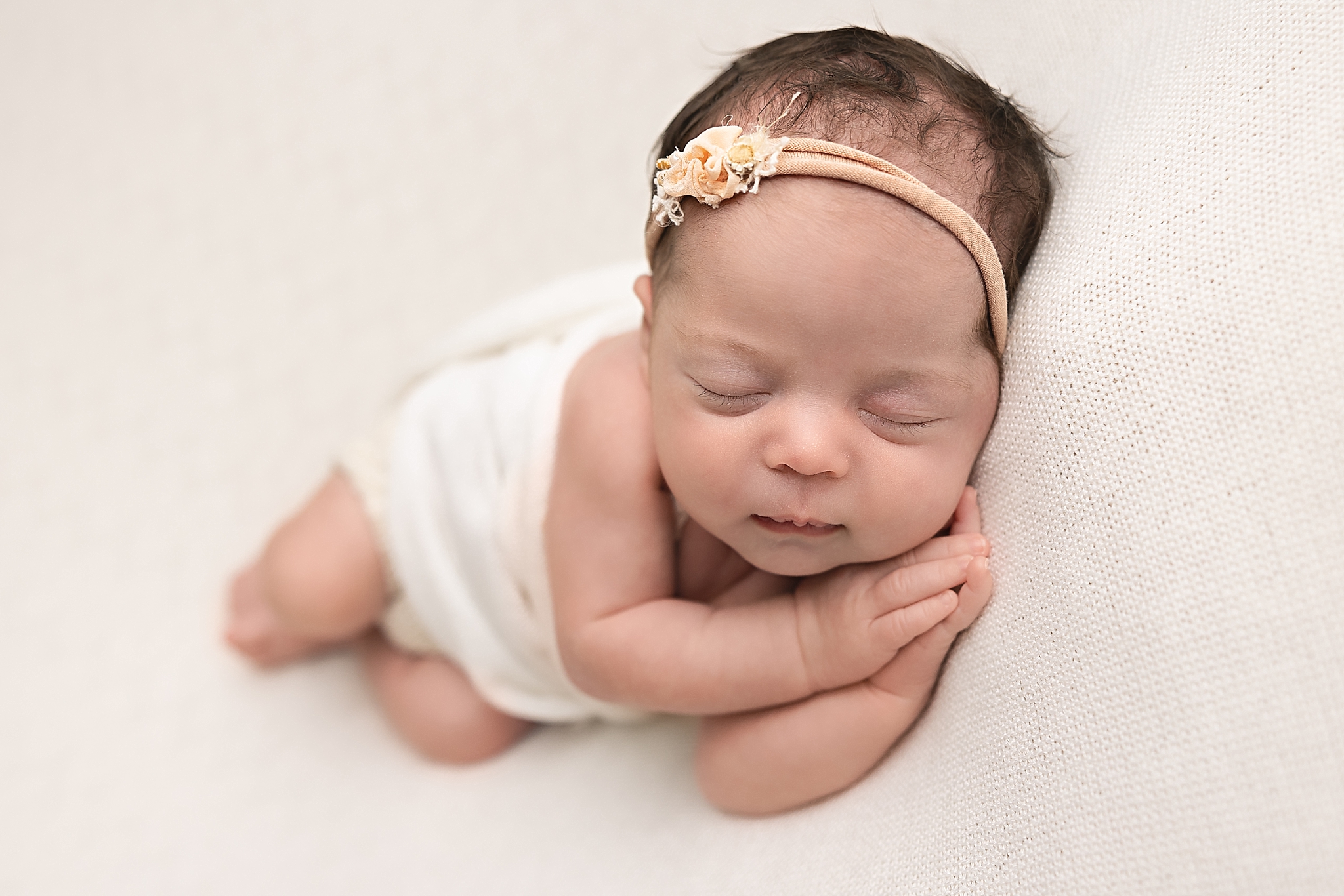newborn baby wrapped in white sleeping on her hands Grasshopper Boutique Portland