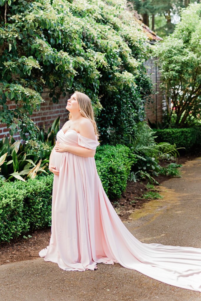 mom to be in pink gown looking up in a garden Portland Baby Shower Venues