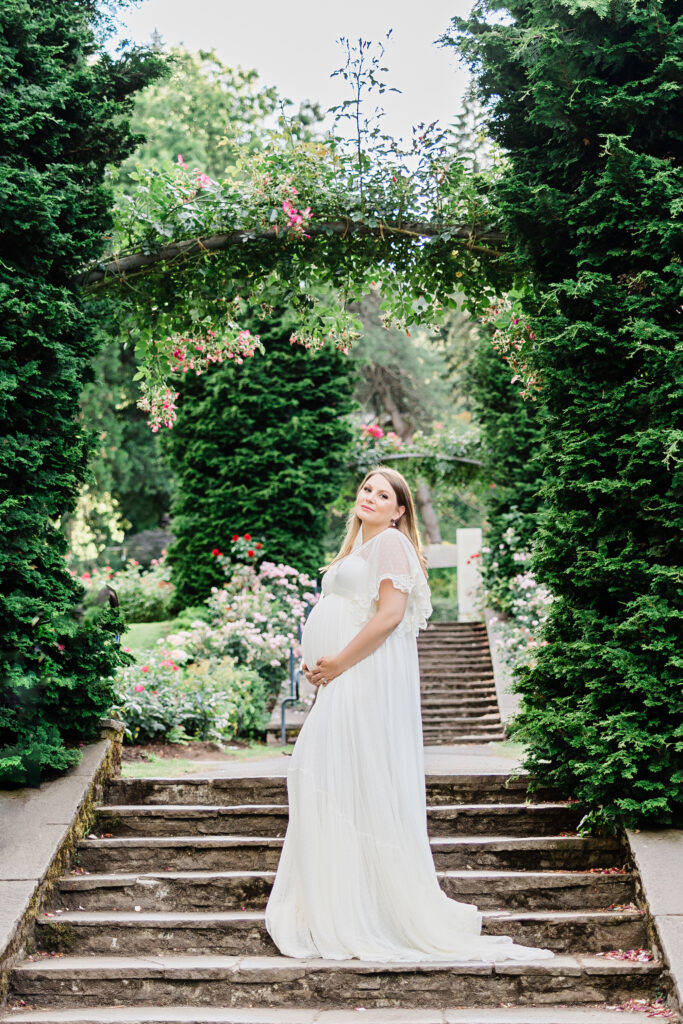mom to be in white gown standing in a garden Portland Baby Shower Venues