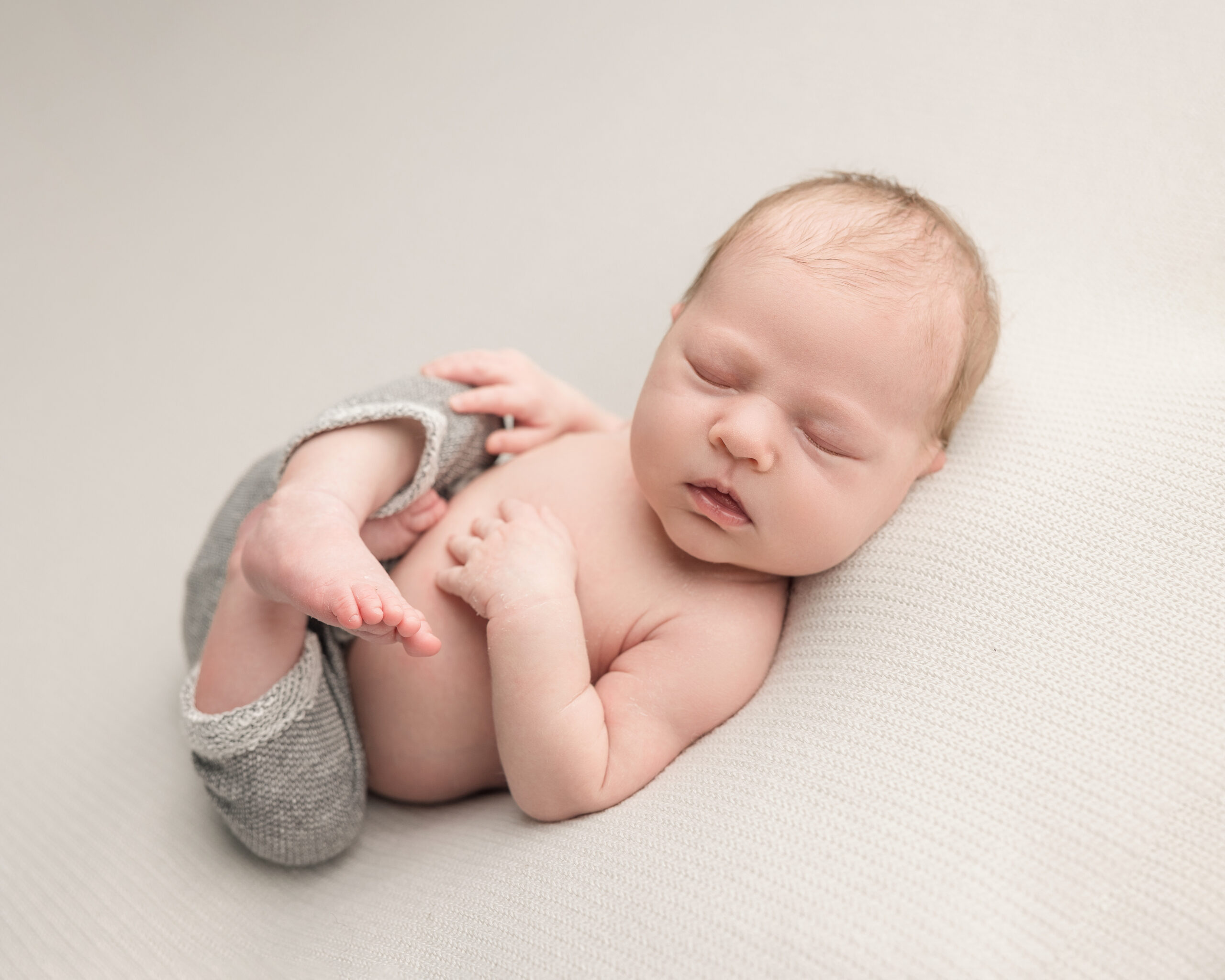Baby in neutral colored pants relaxing