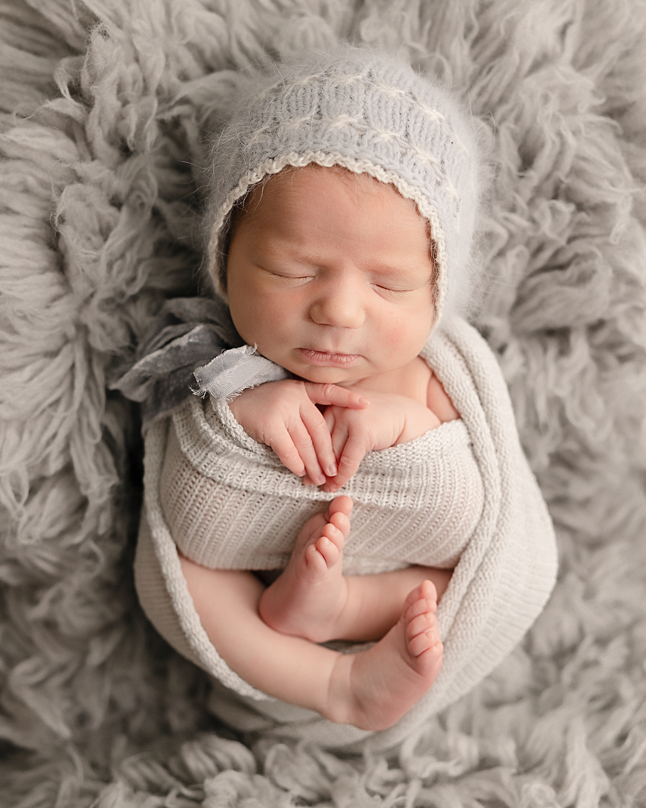baby wrapped in a neutral wrap and hat on a carpet Tidee Didee Portland