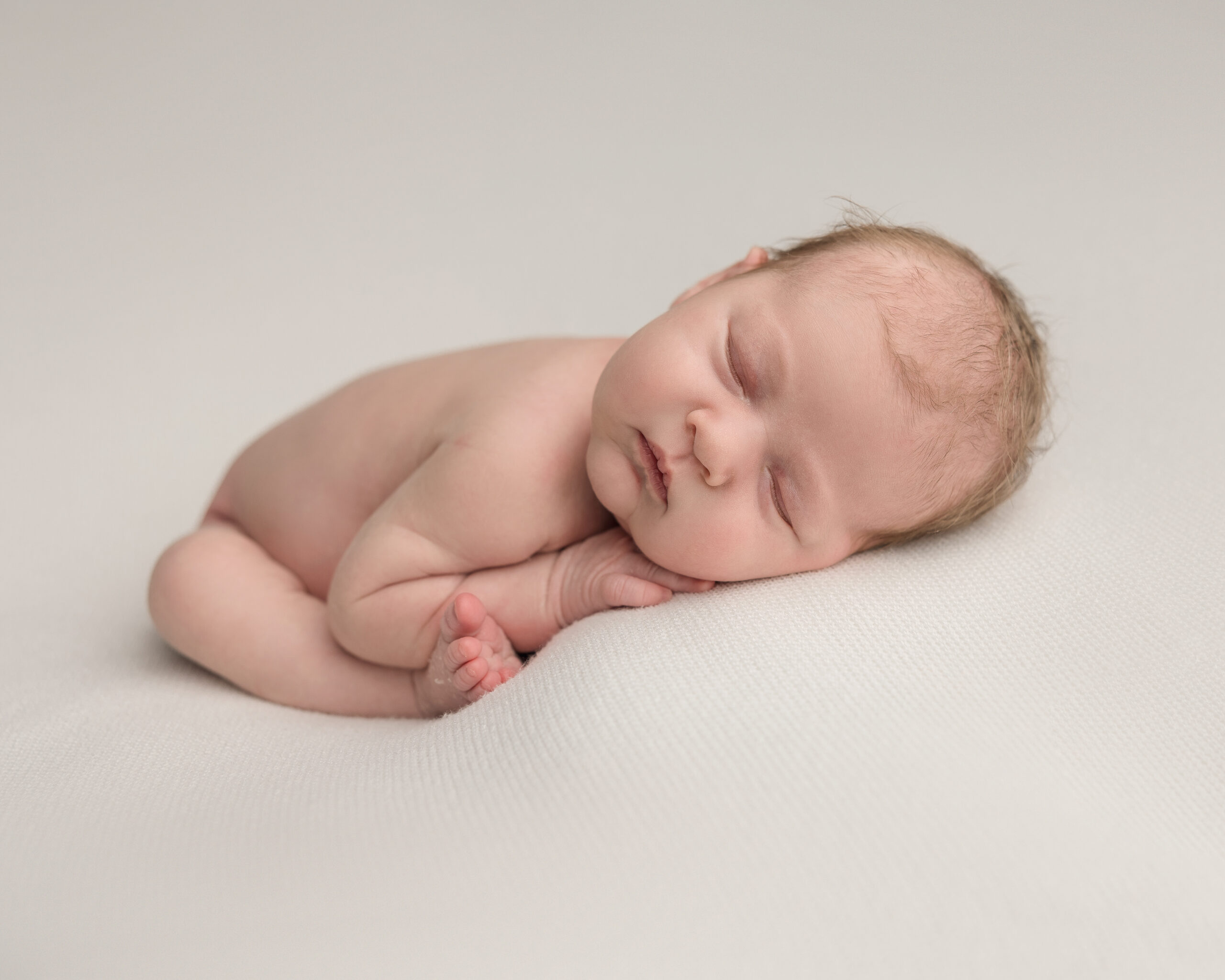 Newborn baby laying on a neutral cloth