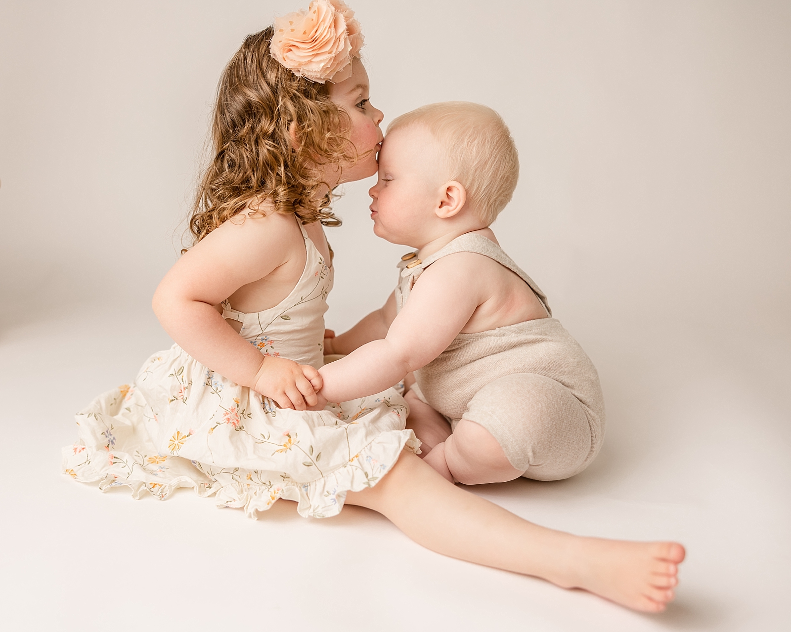 young girl kissing her baby brother on the forehead