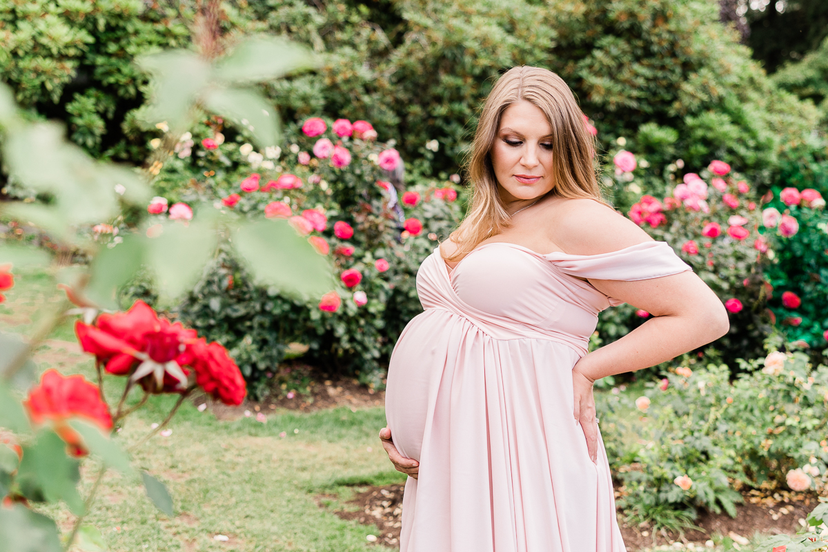 mom to be in pink gown holding her back and bump Portland Postpartum Doula