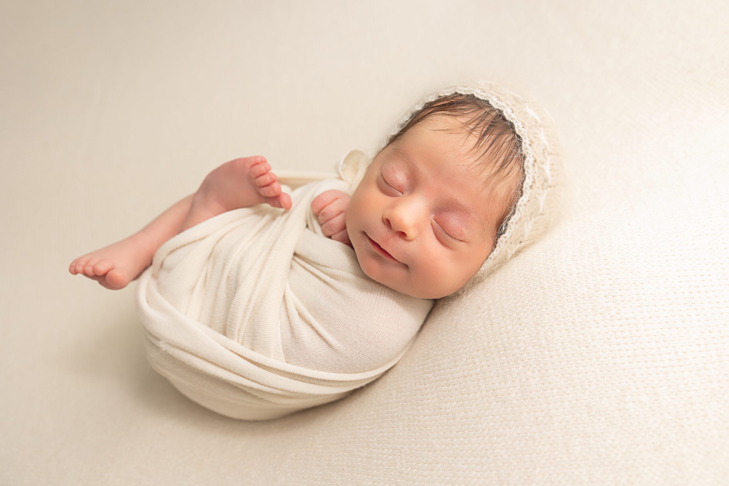 newborn baby in cream wrap slightly smiling Portland Postpartum Doula