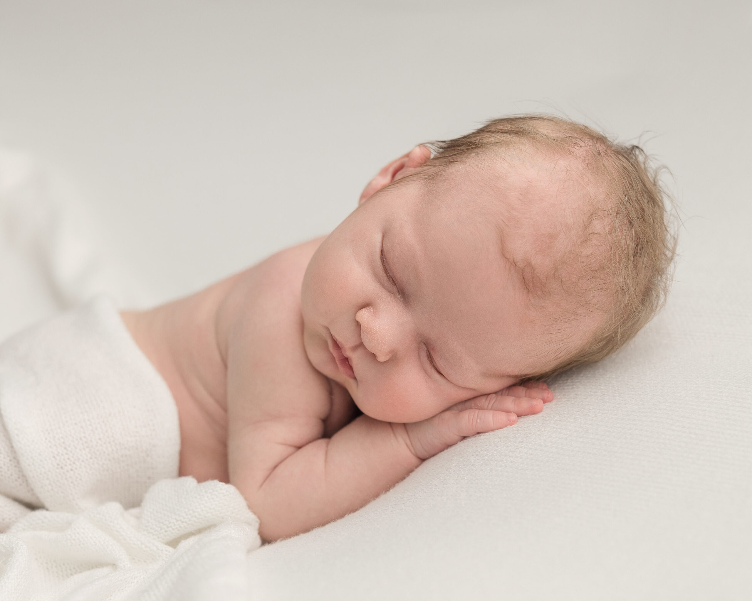 newborn baby with cream cloth sleeping on their hands Vivante Midwifery