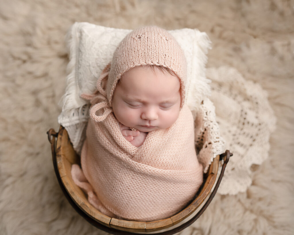newborn baby wrapped in pink laying in a bowl