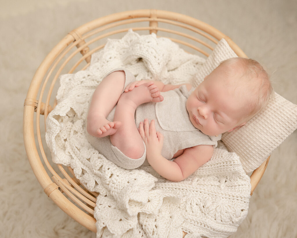 newborn baby in neutral onesie laying in a basket Sweetpea’s Portland