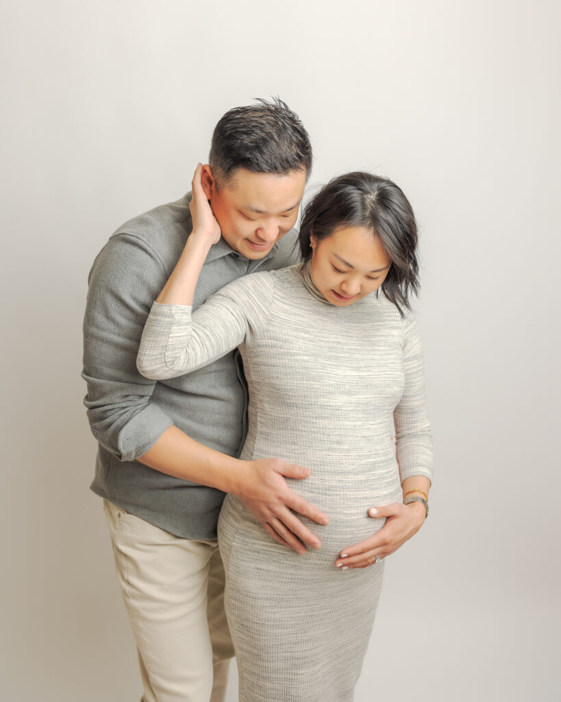 mom and dad to be in grey outfits holding each other and the bump ABC Doula