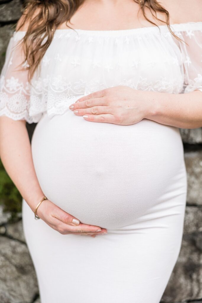 Close up of a mom's pregnant bump in a white dress