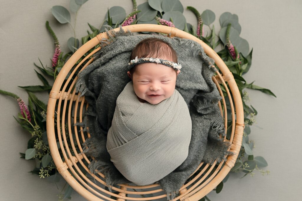newborn baby girl wrapped in green smiling in a basket Portland Doula Love