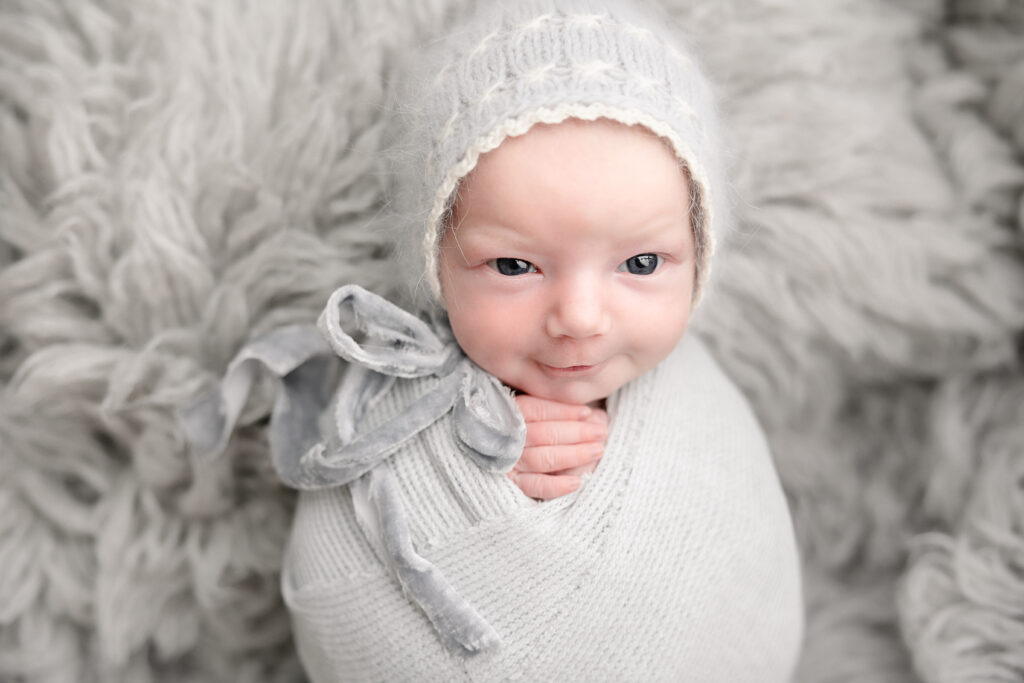 newborn baby in grey smiling with eyes wide open portland oregon nanny agency