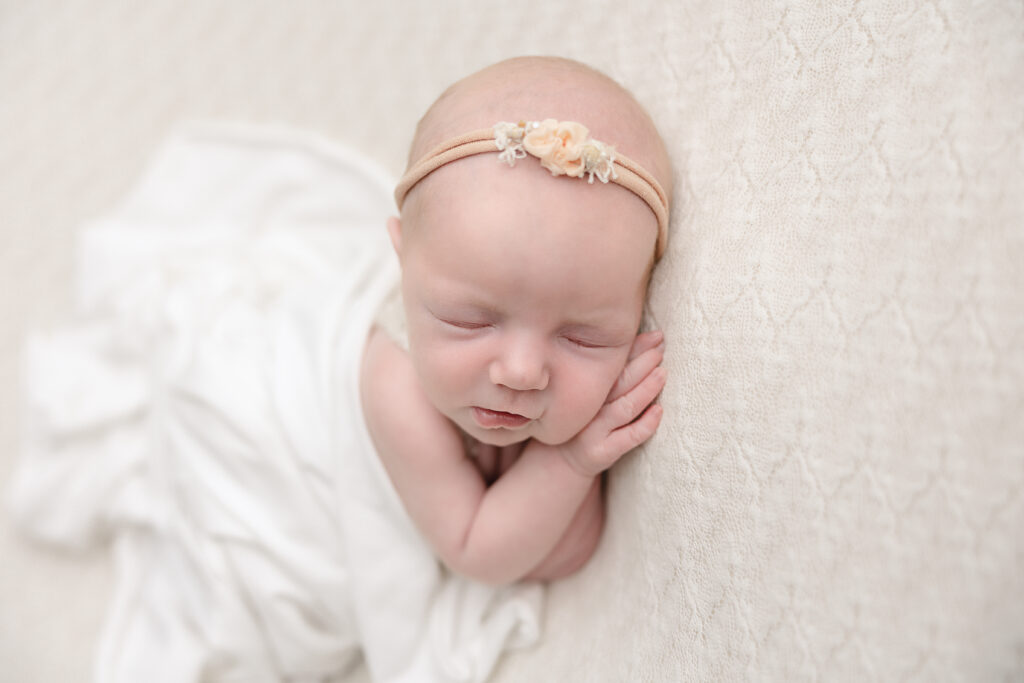 newborn baby in white blanket sleeping on her hands portland oregon nanny agency
