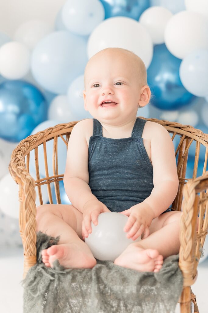 Little boy in blue overalls laughing in a chair Oodles of Toys