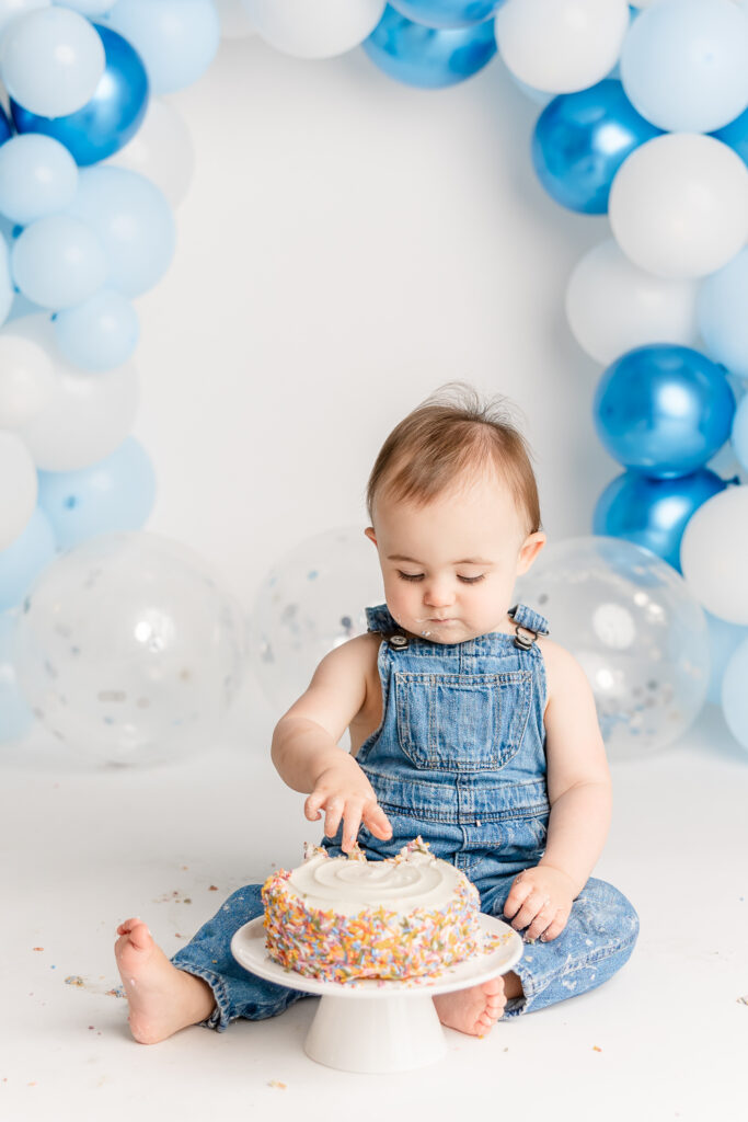 little boy in blue overalls eating a cake for his birthday