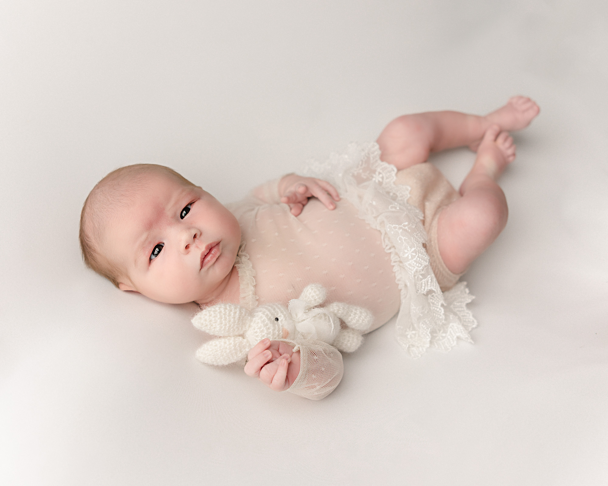 newborn baby in sheer white dress holding a bunny stuffed animal Balanced Family Natural Medicine
