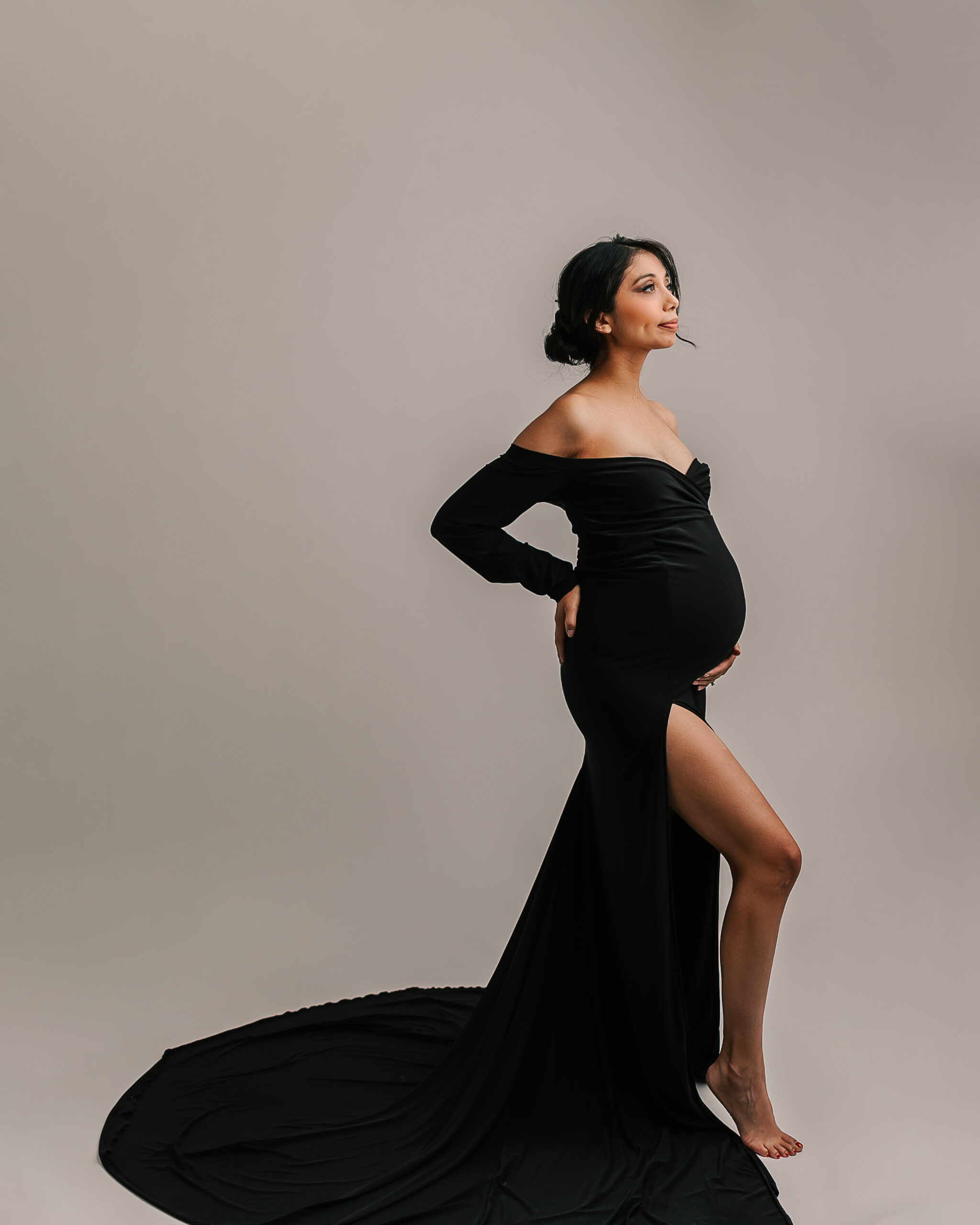 pregnant woman in long sleeved black maternity gown in a studio Inner Serenity Midwifery