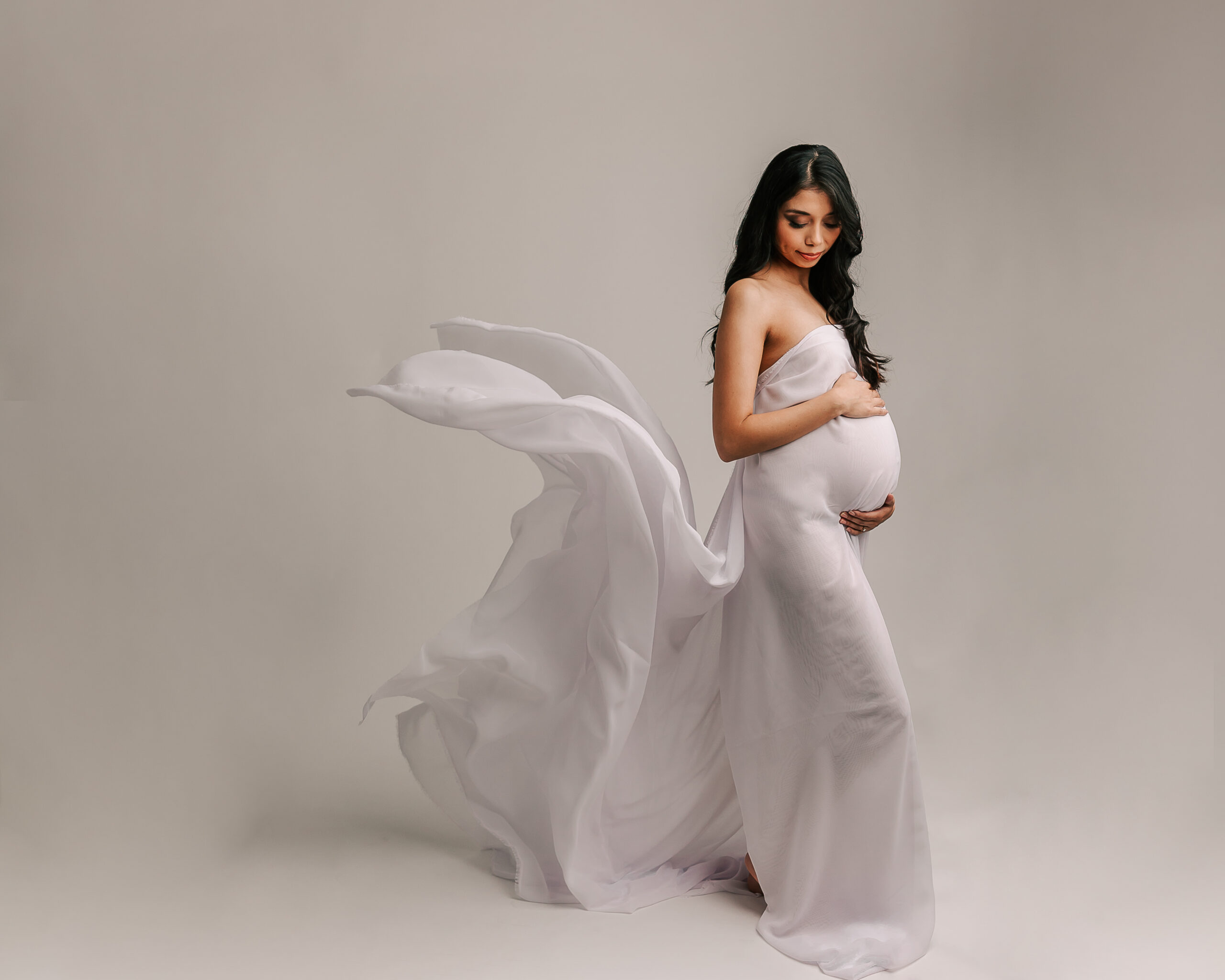 mom to be in a grey maternity gown with her train flying Inner Serenity Midwifery