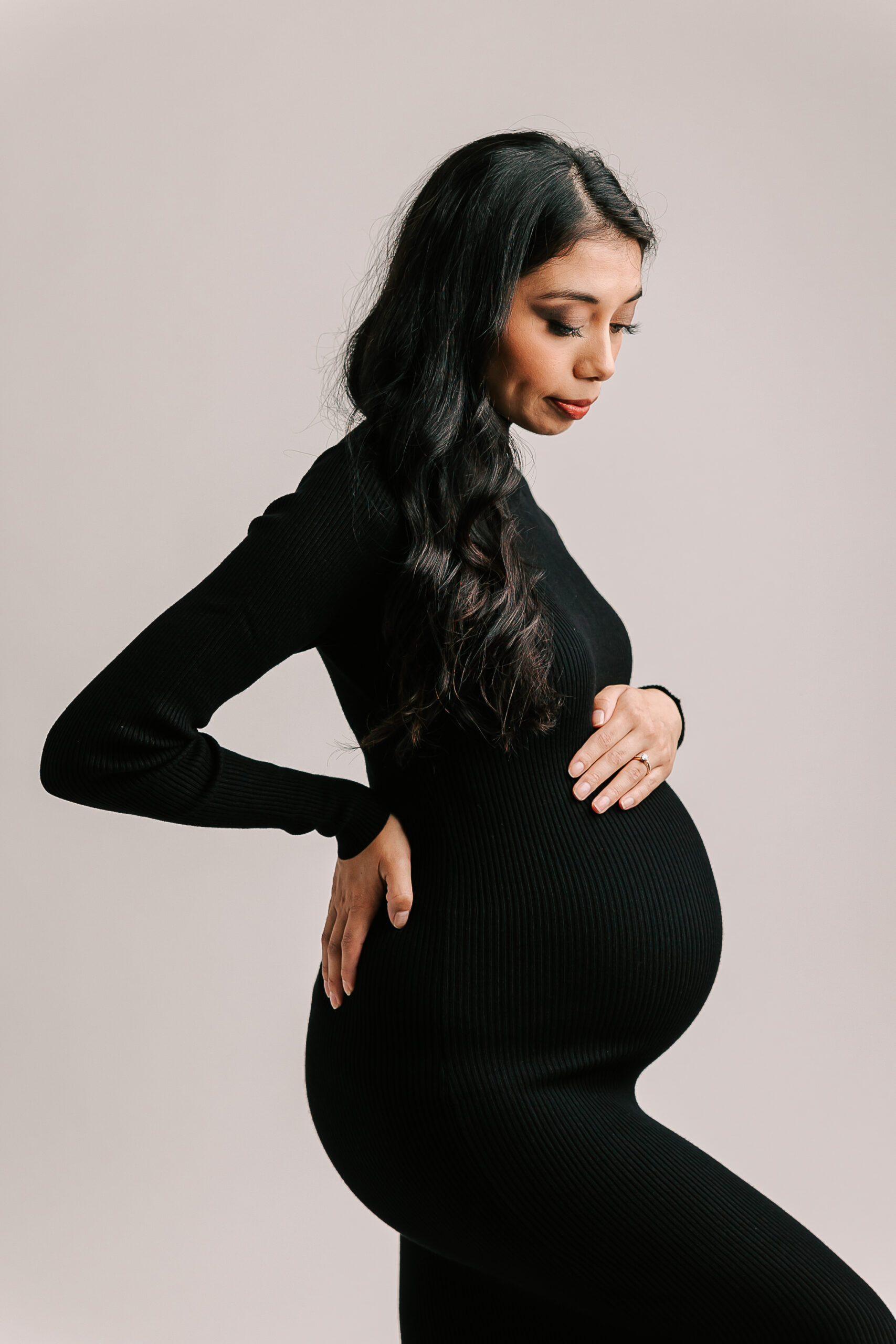 mom to be in black maternity gown holding her bump and looking down ItsaBelly