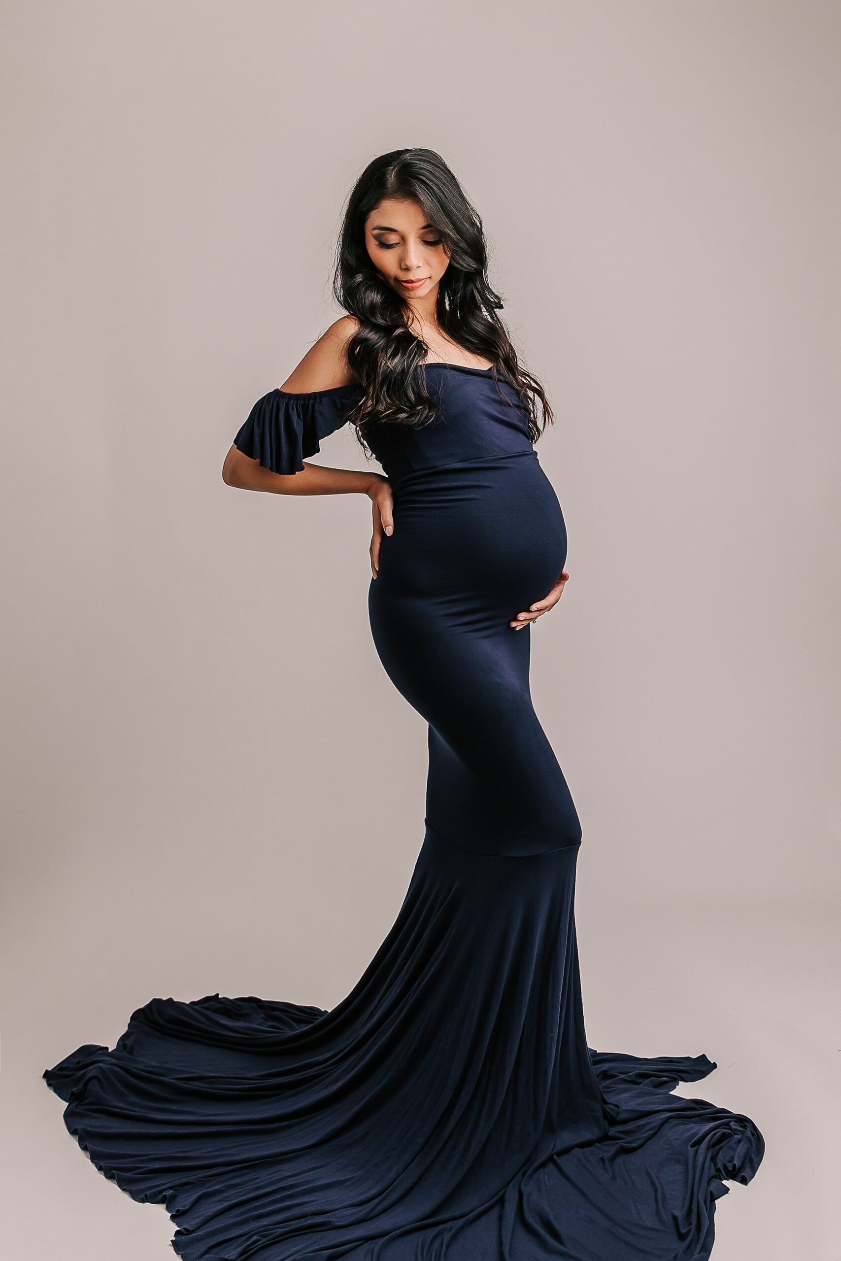 pregnant mom in navy maternity gown looking towards her bump Motherseed Midwifery