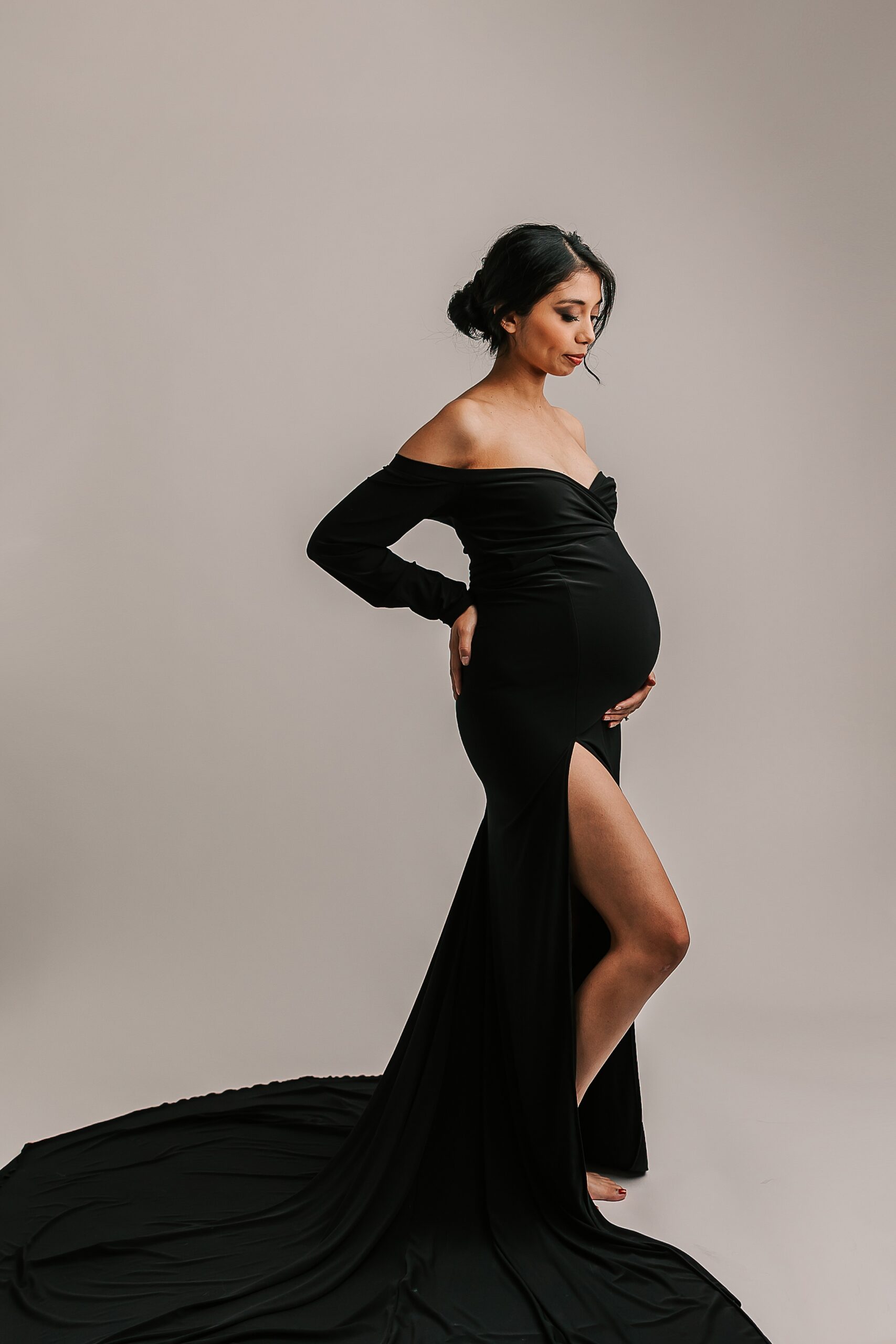 mom in black maternity gown with her leg popped and holding her bump Portland Doula Collective