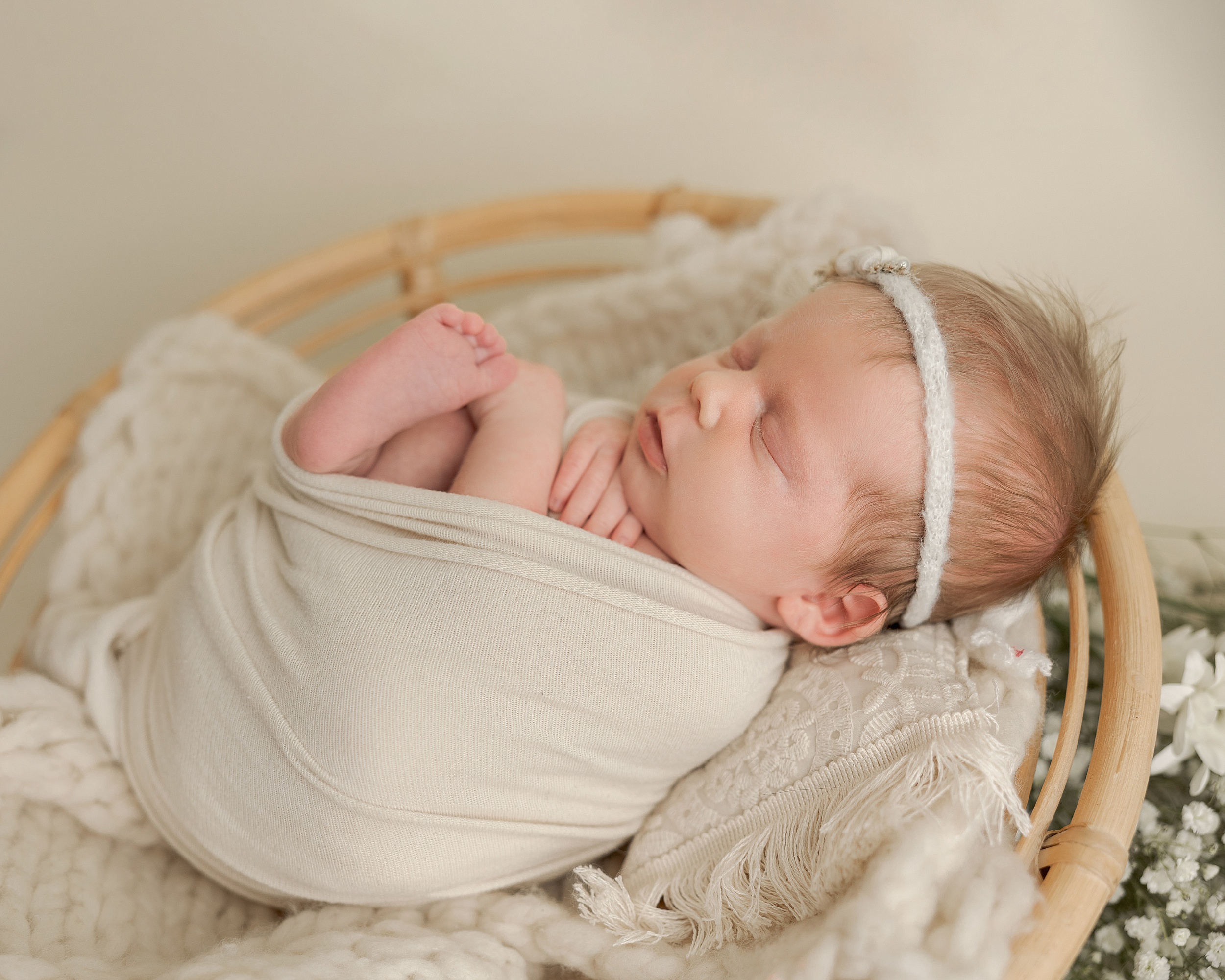 newborn baby girl wrapped in neutral cloth sleeping in a basket Rosehip Midwifery