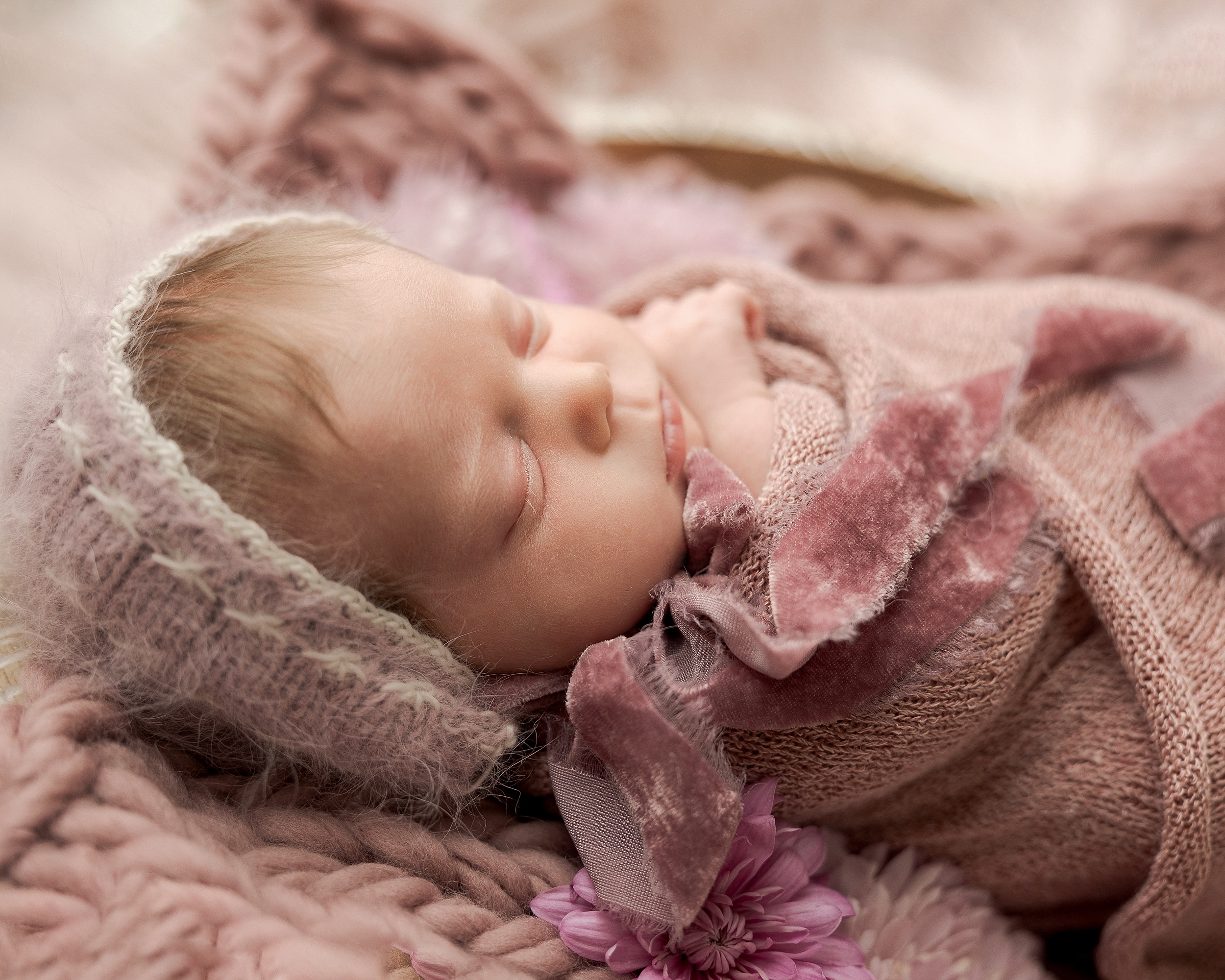 newborn baby girl wrapped in purple with a matching hat sleeping