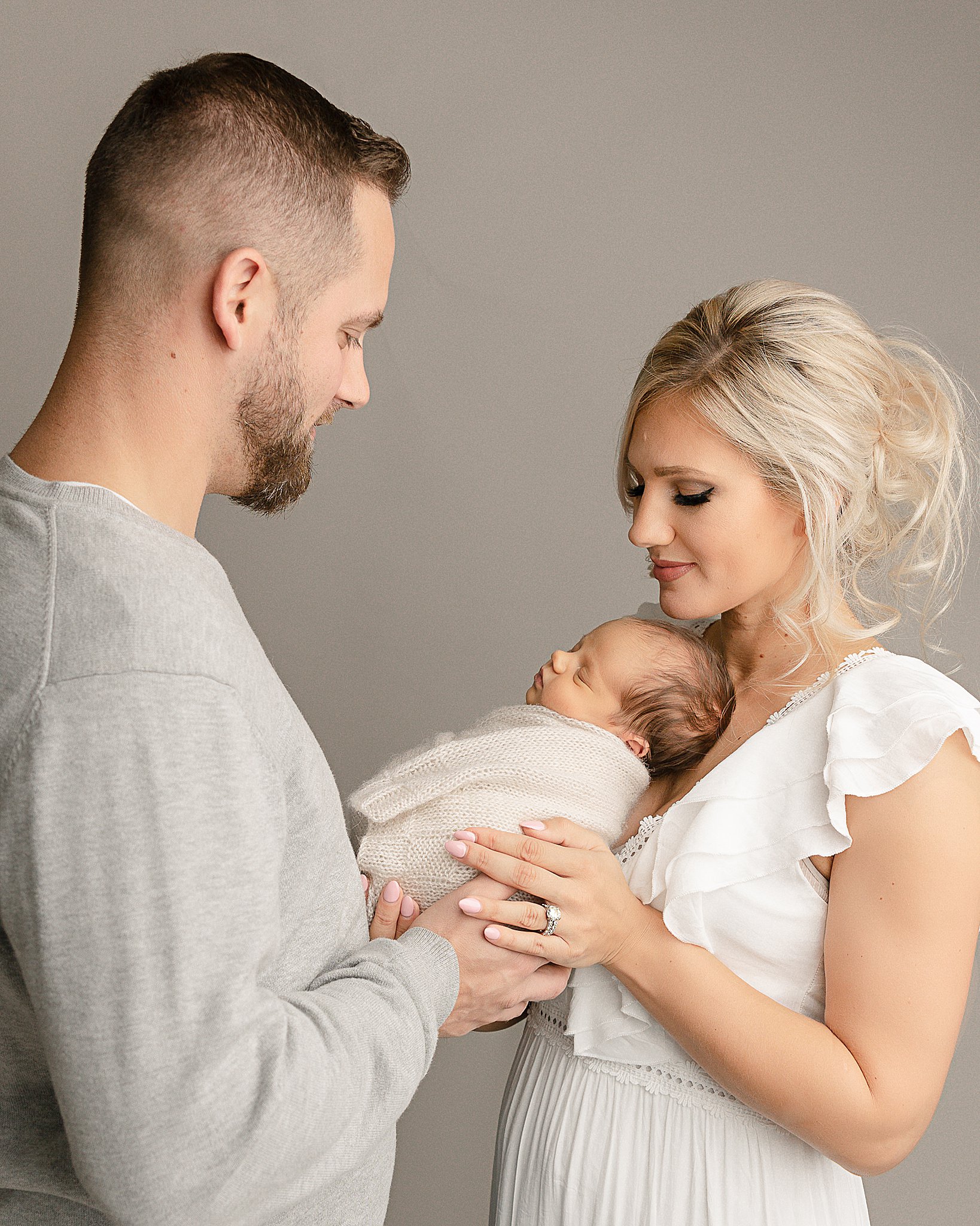 mom and dad holding their newborn baby in the studio Wisdom Wellness