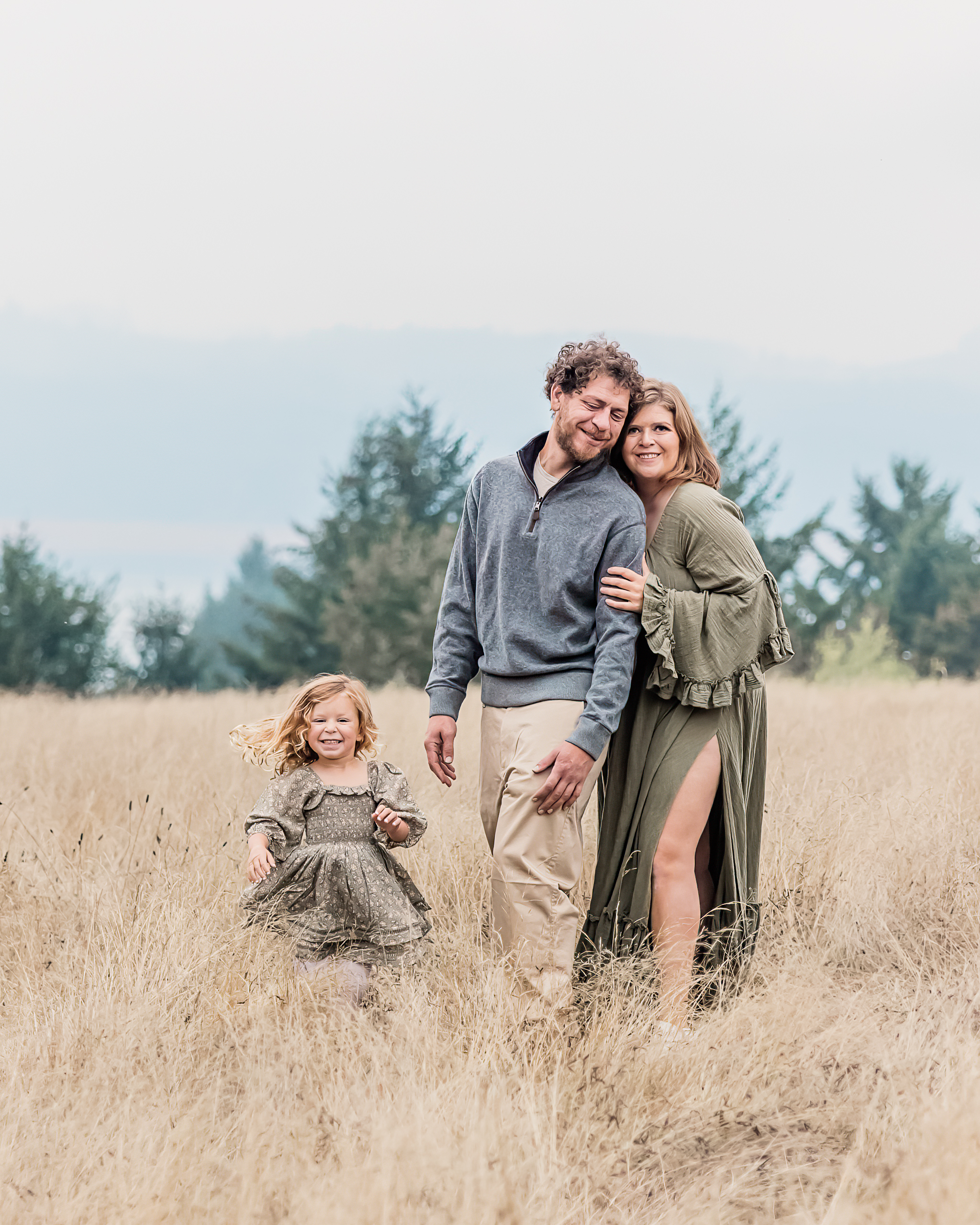 family of three holding on to one another in a large open field near portland yoga studios