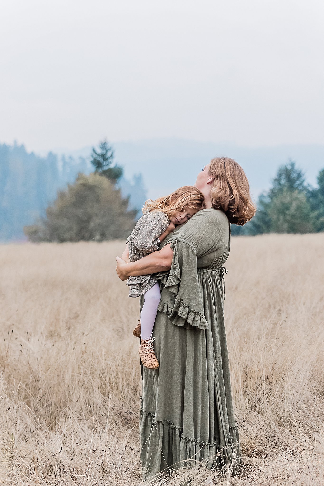 mom holding her little girl in a field near Beaverton Yoga Studios