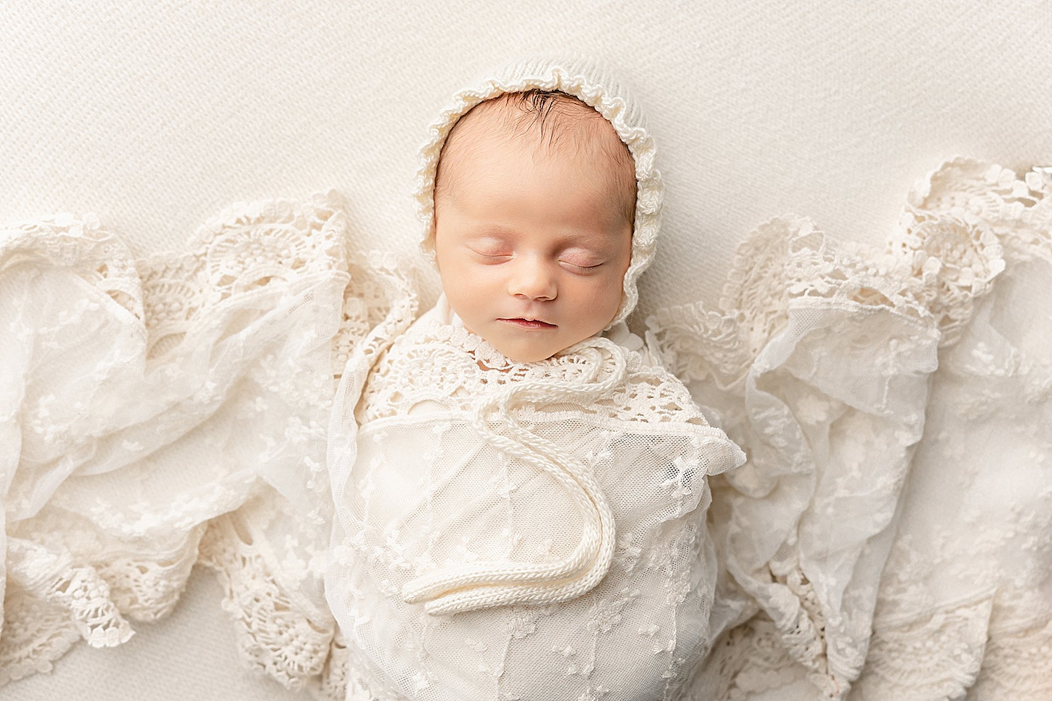 newborn baby girl wrapped in white with a bonnet Portland Lactation Consultant