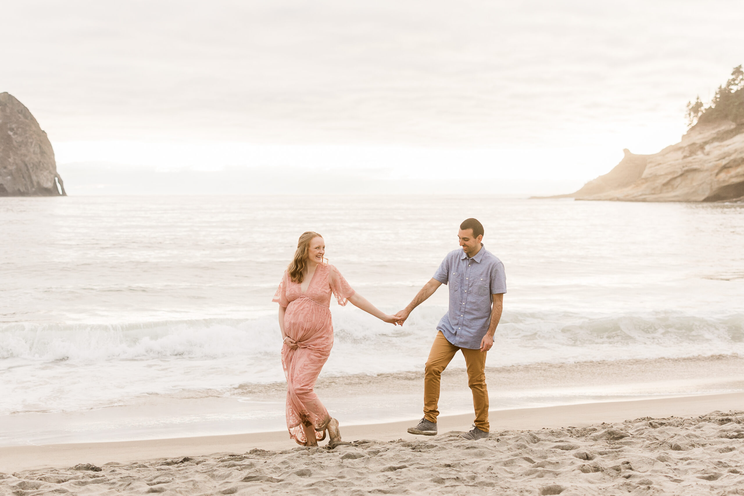 mom to be walking hand in hand with her husband on the beach near Portland Prenatal Massage